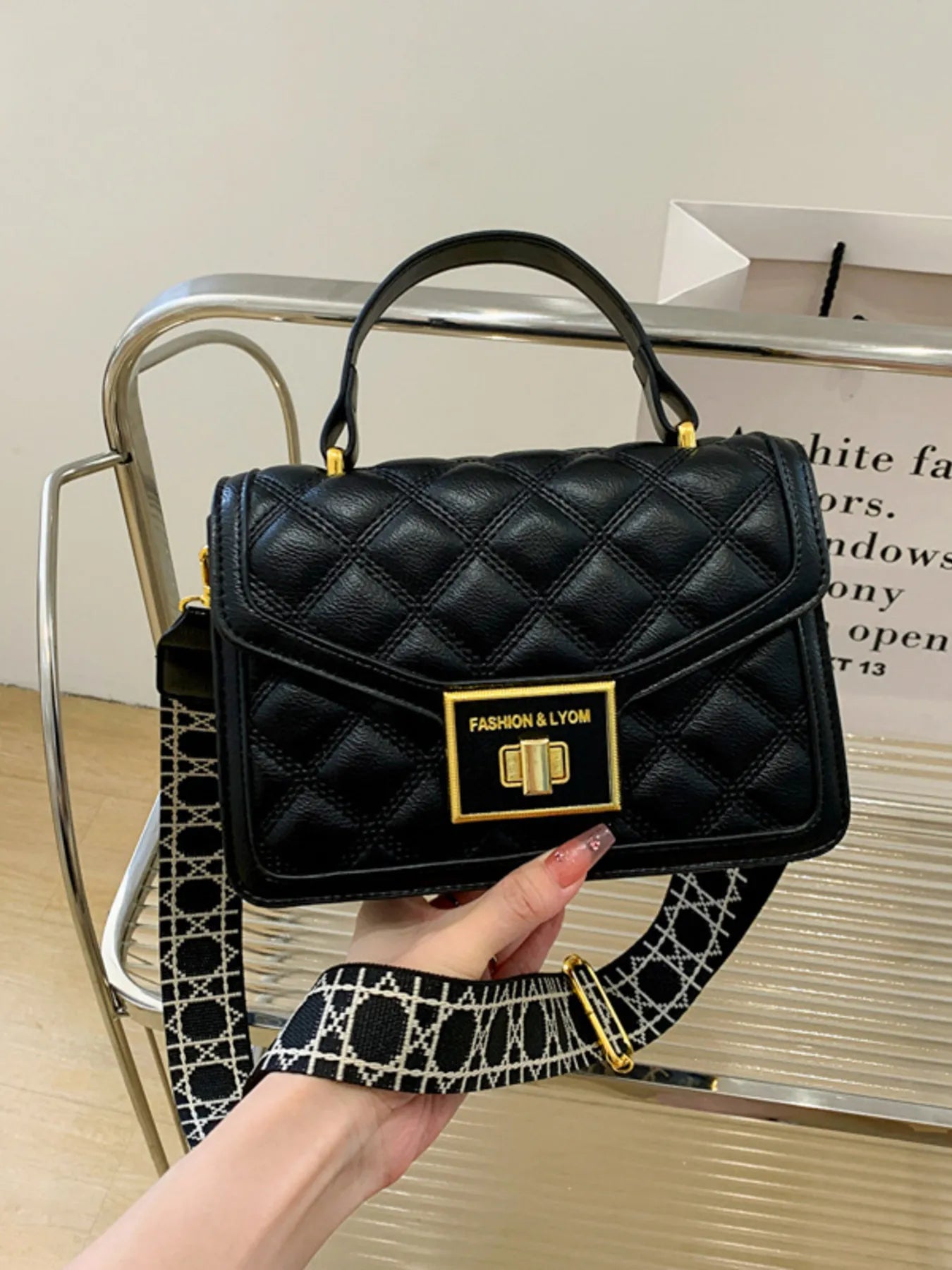 Woman’s hand holding black handbag with quilted design
