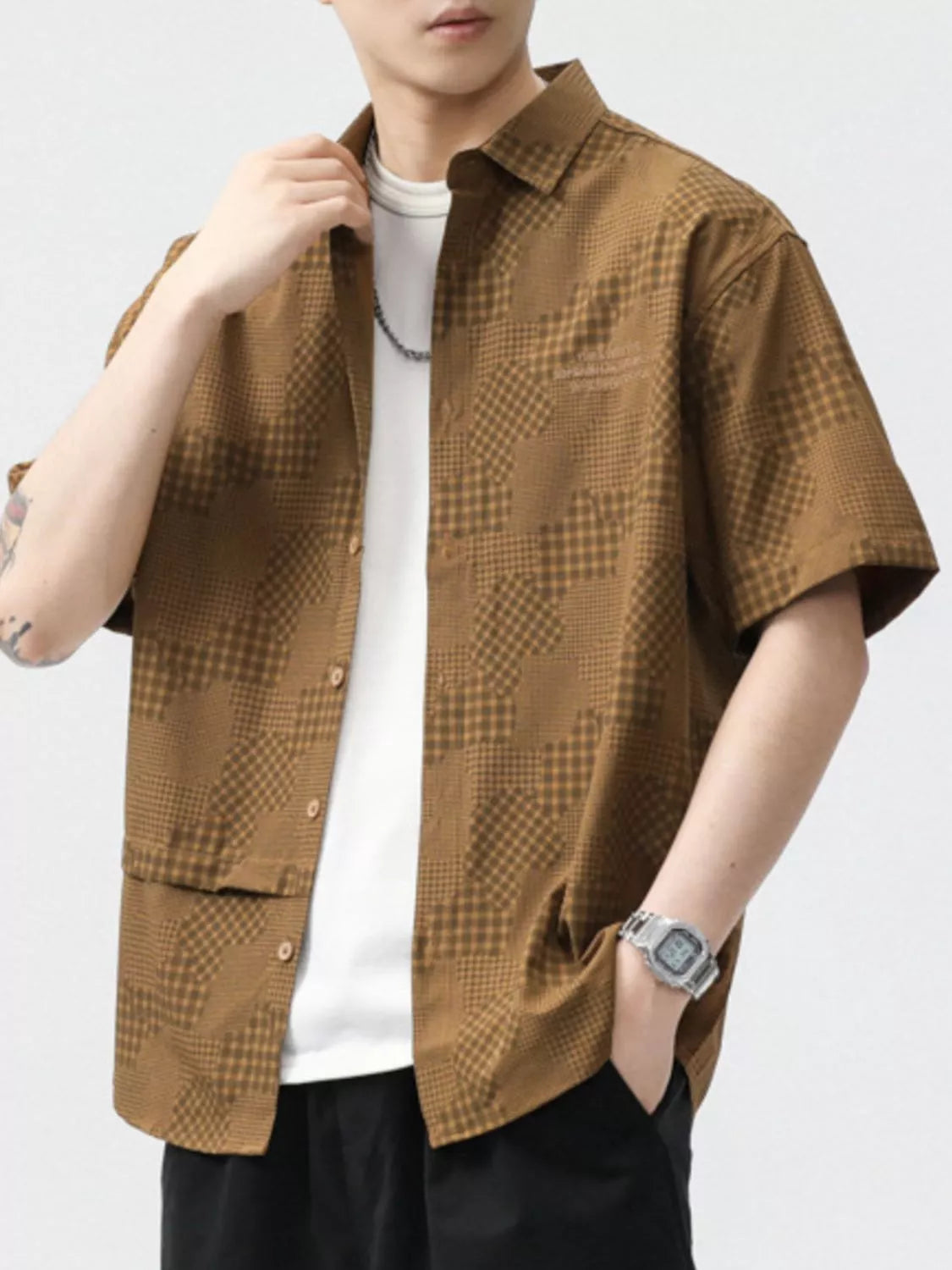 Person wearing a brown checkered shirt over a white t-shirt on a light gray background