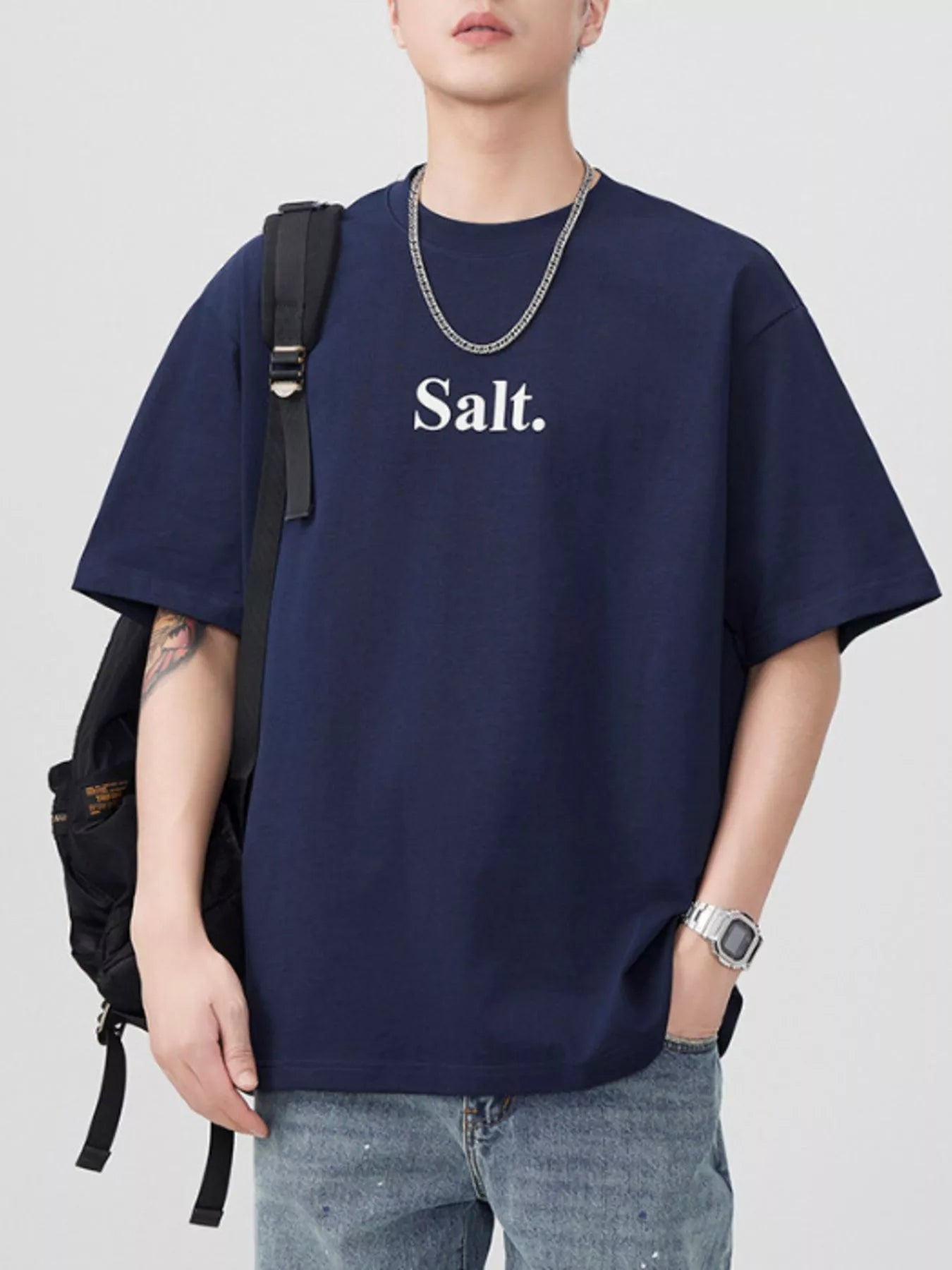 Person wearing a navy blue t-shirt with 'Salt.' text, standing against a plain background