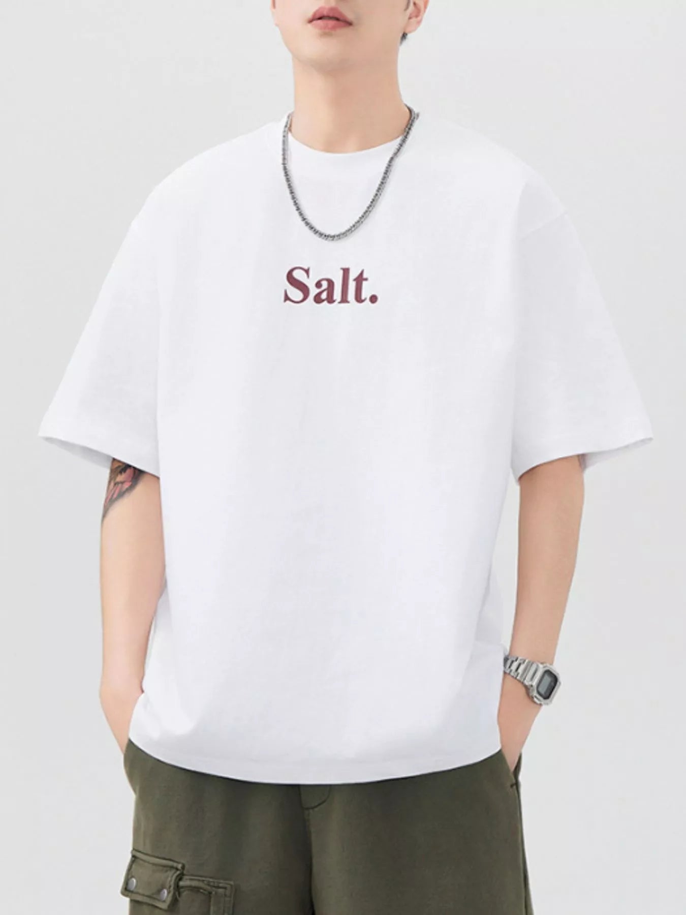 Person wearing a white t-shirt with 'Salt.' text on a plain background