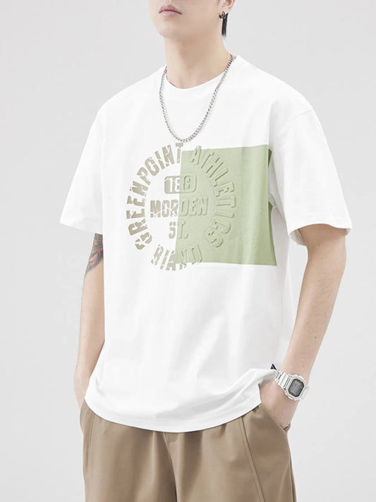 Person wearing a white t-shirt with a green graphic design on a plain background