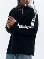 Person wearing a black long sleeve shirt with white stripes on a plain background