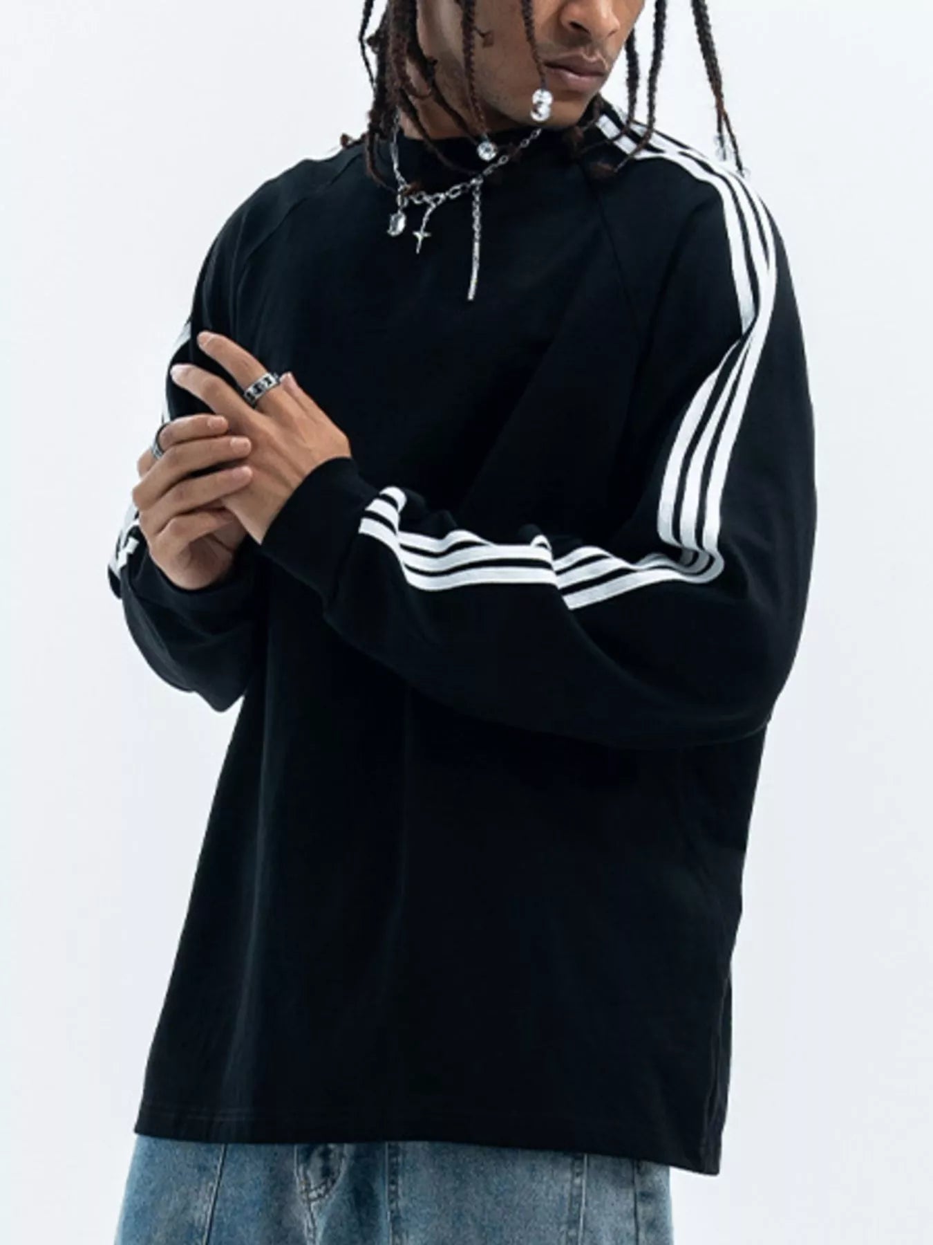 Person wearing a black long sleeve shirt with white stripes on a plain background