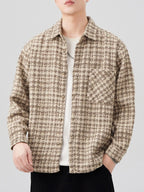 Person wearing a patterned shirt over a plain shirt on a light gray background