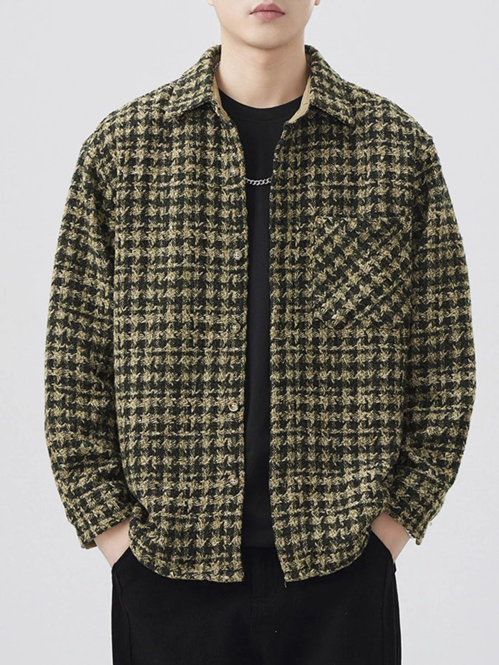 Person wearing a houndstooth patterned shirt over a black t-shirt on a white background