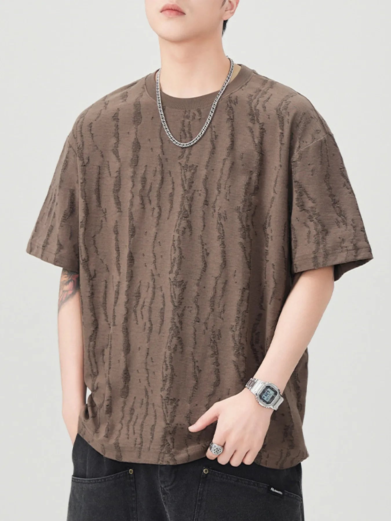 Person wearing a brown patterned t-shirt on a plain background