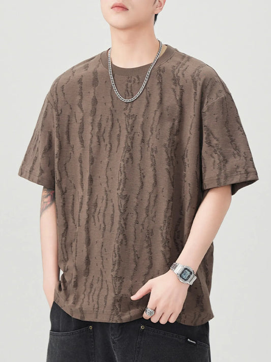 Person wearing a brown patterned t-shirt on a plain background