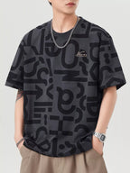 Person wearing a black patterned t-shirt with a brand logo on a light gray background