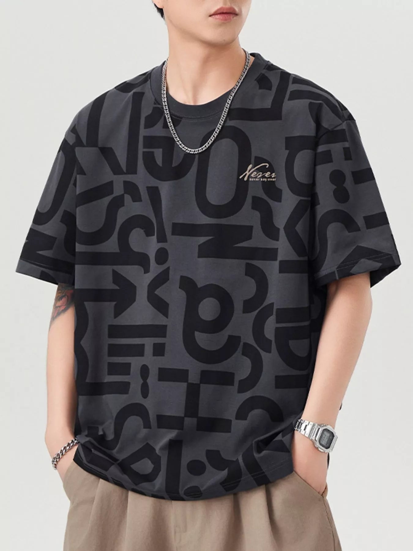 Person wearing a black patterned t-shirt with a brand logo on a light gray background