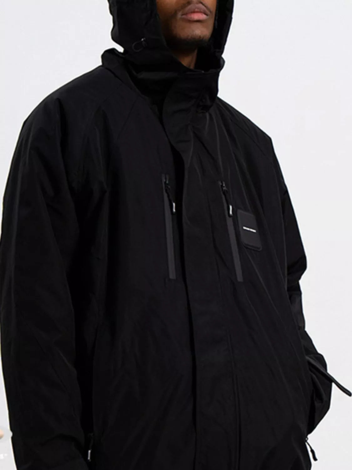 Person wearing a black hooded jacket on a white background