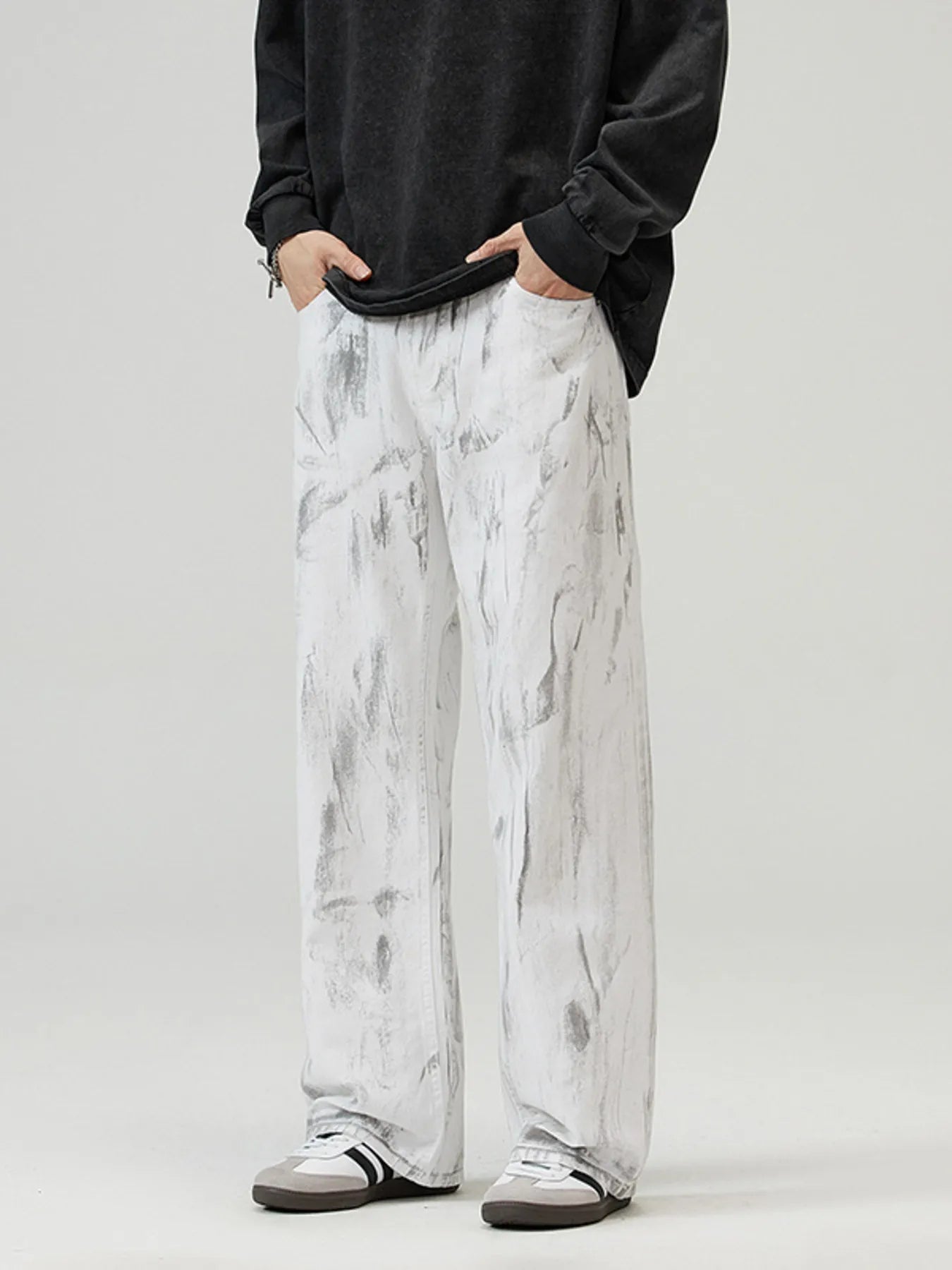 Person wearing black long-sleeve shirt and white marbled pants on a plain background